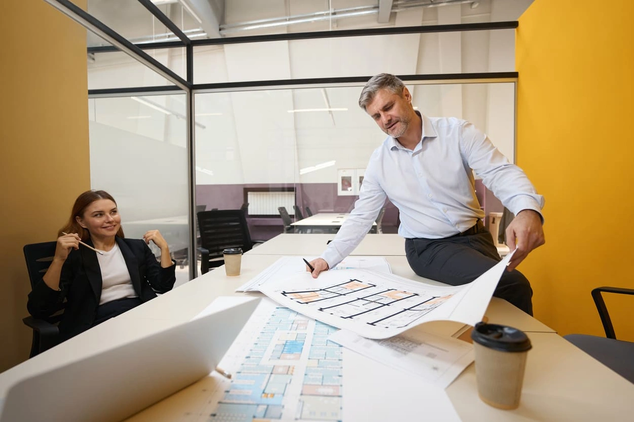 Partners creating a printout of a new office layout to generate excitement Partners creating a printout of a new office layout to generate excitement