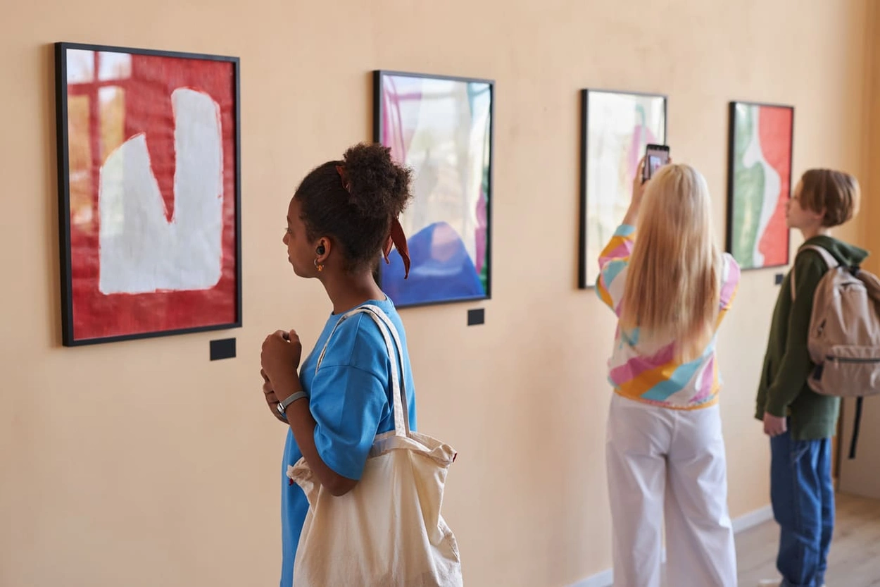 Group of teenagers looking at abstract art prints in an art gallery
