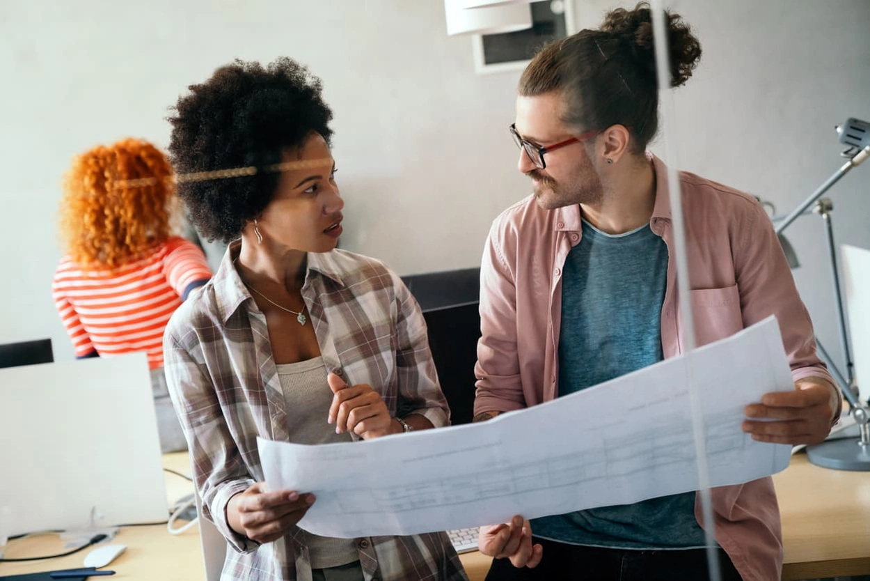 Coworkers discussing how to prevent large format printing mistakes Coworkers discussing how to prevent large format printing mistakes