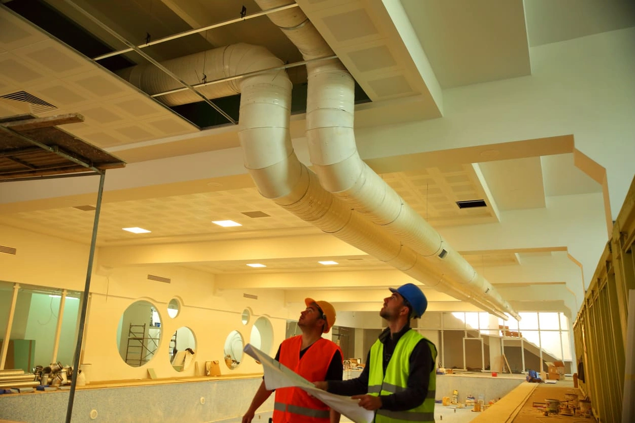 Construction workers using blueprints to ensure the correct placement of internal fixtures Construction workers using blueprints to ensure the correct placement of internal fixtures