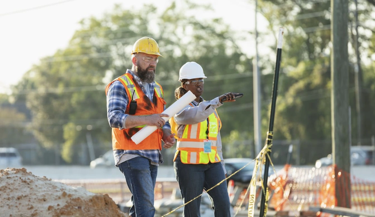Construction workers using mobile devices and newly printed blueprints to stay on top of changes Construction workers using mobile devices and newly printed blueprints to stay on top of changes