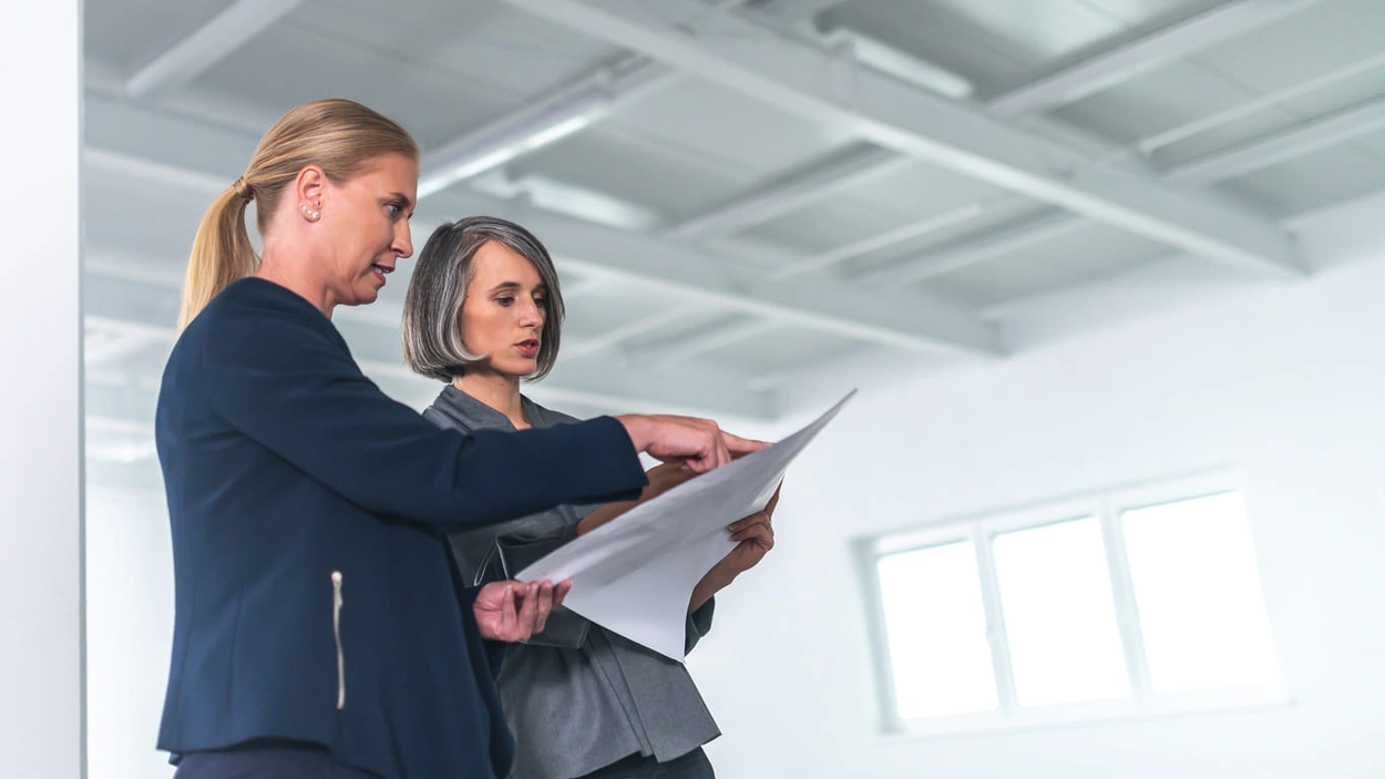 Two coworkers looking at blueprints with print errors from old printheads