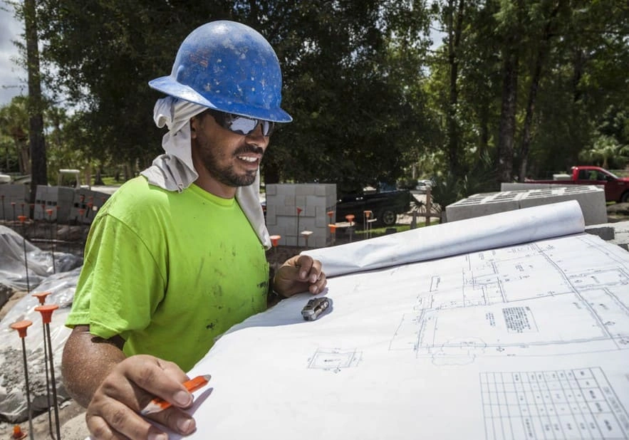Construction technician reviewing site planning and landscape documents before starting a new phase of construction Construction technician reviewing site planning and landscape documents before starting a new phase of construction