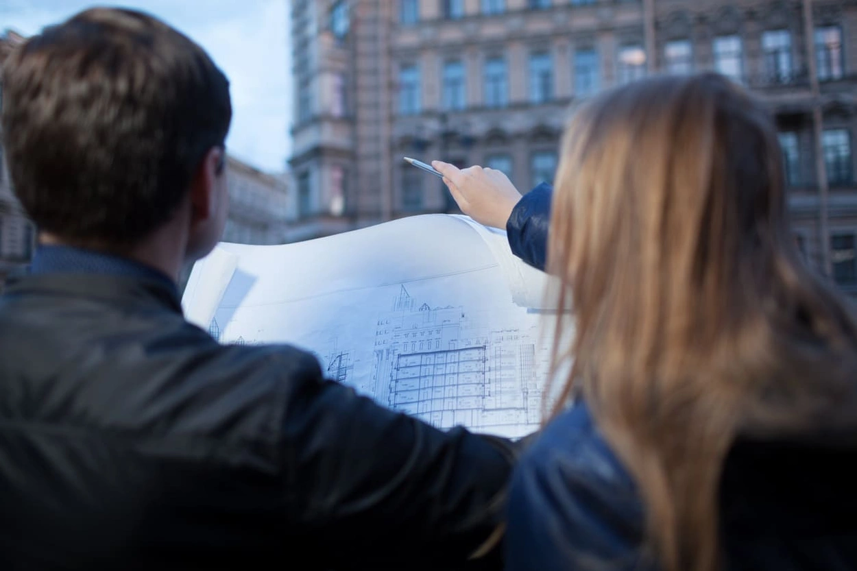 People looking at a detailed blueprint of an old building People looking at a detailed blueprint of an old building