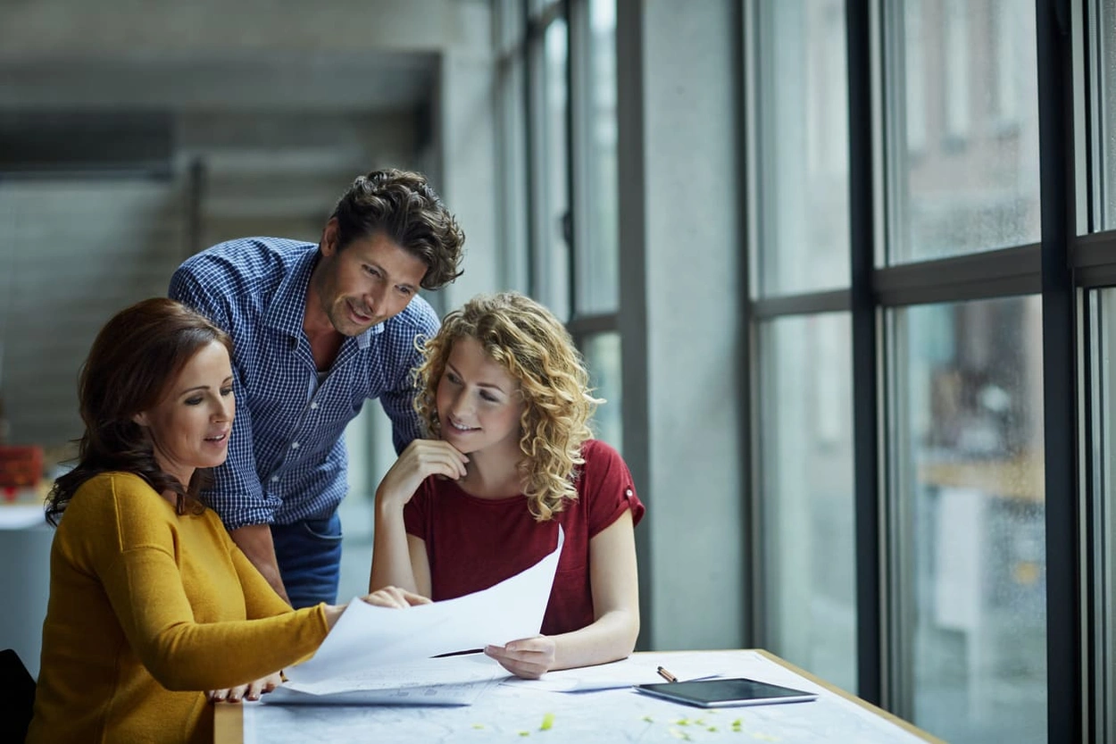 AEC employees discuss CAD documents printed by a large format multifunction printer
