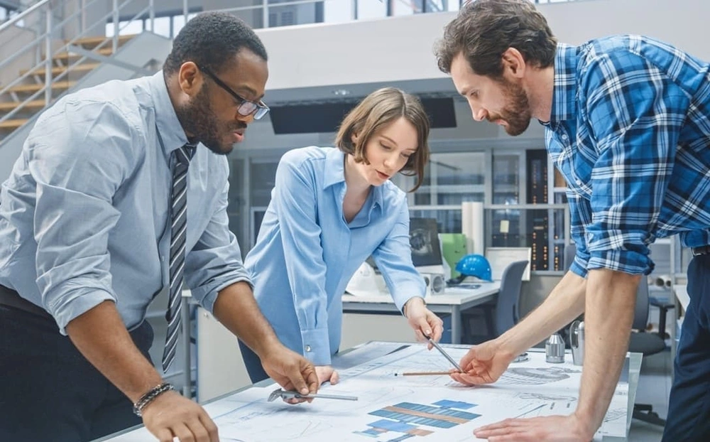 AEC professionals studying architectural blueprints after printing out blueprints for a project AEC professionals studying architectural blueprints after printing out blueprints for a project