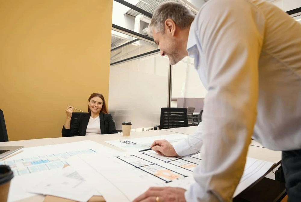 Coworkers reviewing printouts from a large-scale colour plotter printer