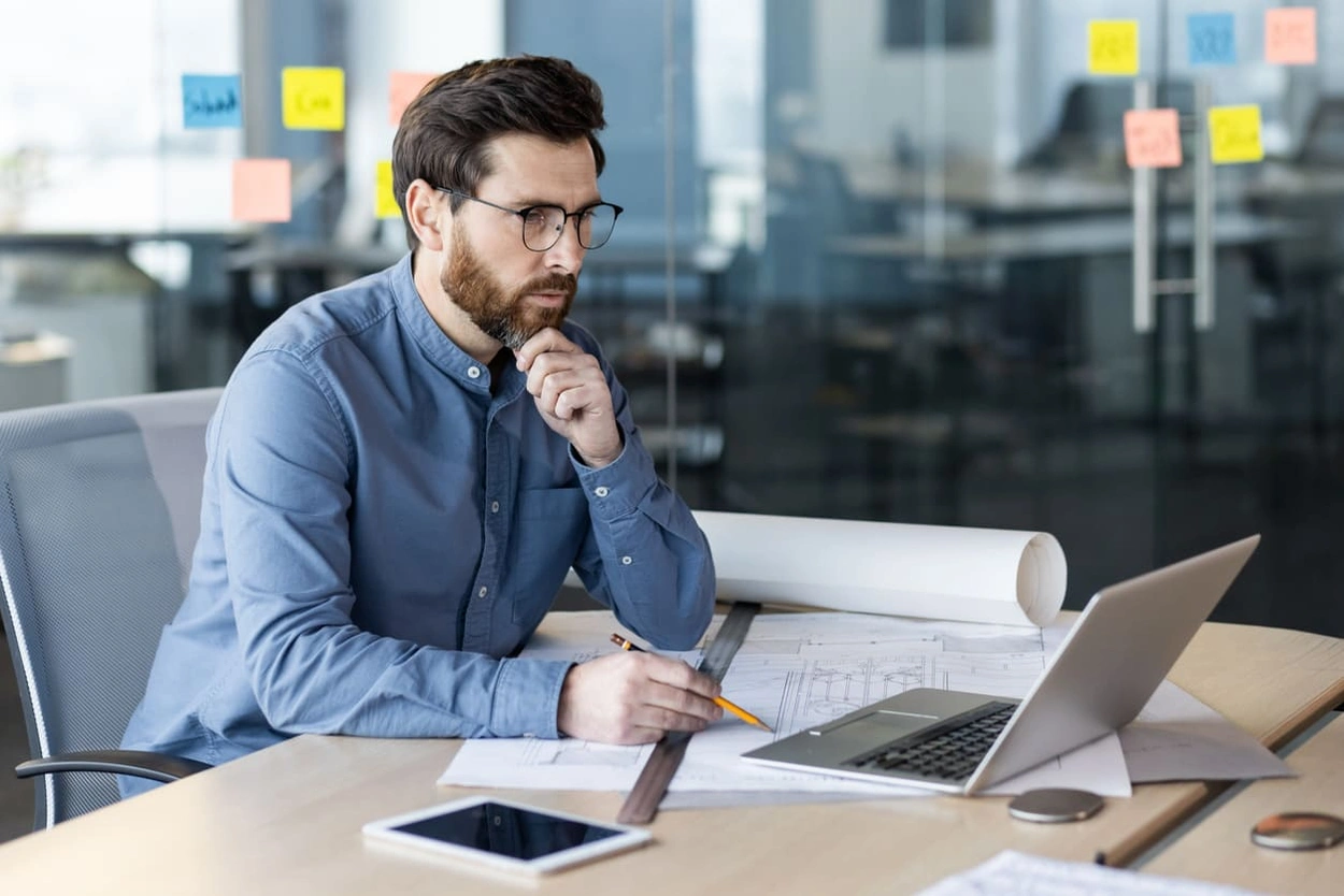 Architect reviewing blueprint edits on his computer after implementing a new wide format scanning workflow Architect reviewing blueprint edits on his computer after implementing a new wide format scanning workflow