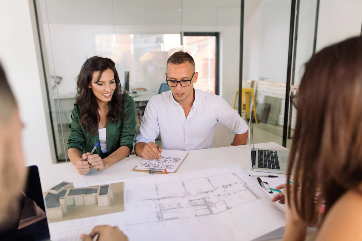 Team reviewing construction blueprints in their office Team reviewing construction blueprints in their office