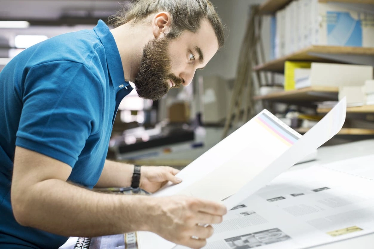 Employee inspecting oversized papers from an in-house plotter