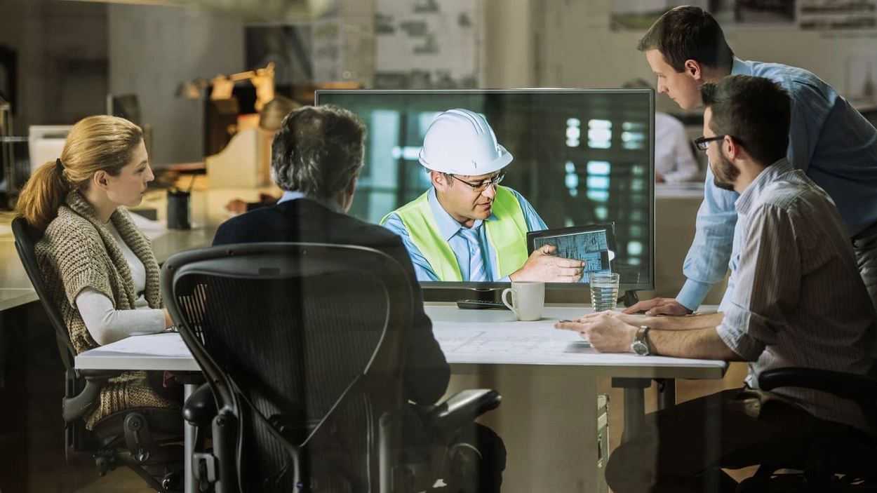 Contractor on a jobsite conducting a conference call and displaying AutoCAD blueprints, which will undoubtedly be printed on plotter paper using a large format printer and scanner or A1 printer