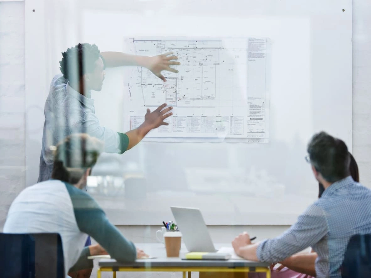 Coworkers reviewing architectural board prints and blueprints before a presentation
