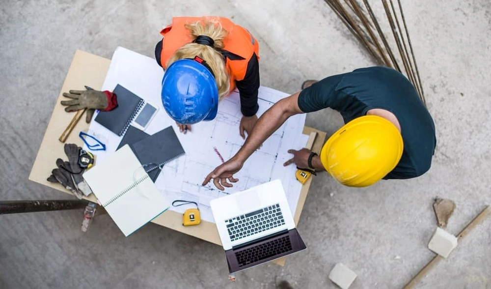 Construction workers securely accessing new blueprints with on-site connectivity and solid cybersecurity in construction Construction workers securely accessing new blueprints with on-site connectivity and solid cybersecurity in construction