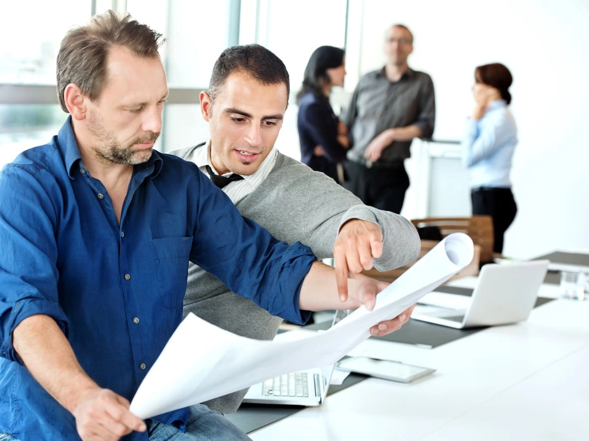 Two co-workers looking at plotter printer plans